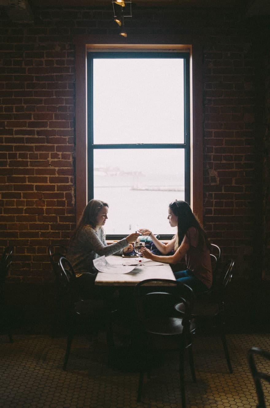 Two girls sitting together and eating icecream in restaurant